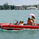 <p><b>Slim Aarons</b>, <i>Sea Drive</i>, c. 1967. Film producer Kevin McClory takes his wife Bobo Segrist and their family for a drive in an 'Amphicar' across the harbour at Nassau. © Slim Aarons</p>