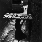 <p><b>W. Eugene Smith</b>, <i>Bernardina Curiel carrying 24 loaves of homed bread to the local bakery, in order to bake them. From the Spanish Village photo-essay. Deleitosa, Spain. 1951.</i></p>